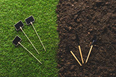 草地上的空黑板和土壤园艺工具的顶部视图