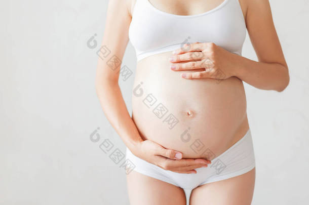 穿着白内裤的孕妇怀孕的年轻女人.
