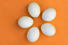 在明亮的橙色背景上的一些白色复活节彩蛋