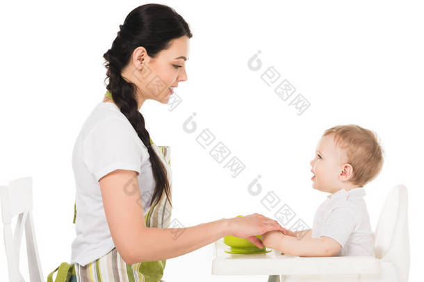 母亲牵手的侧面视图在高脚的小男孩在白色背景隔绝了