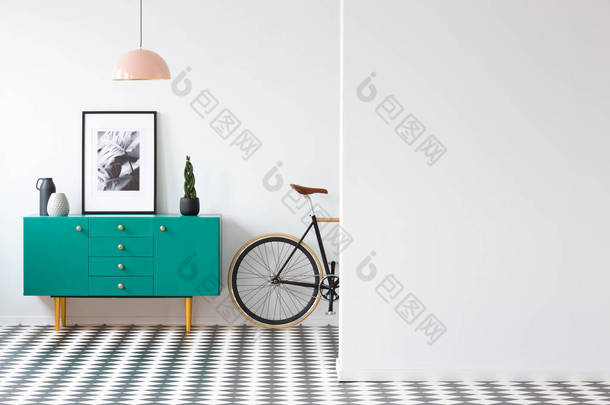 在复古起居室内用自行车和墙上复制空间的绿色橱柜上的植物和海报