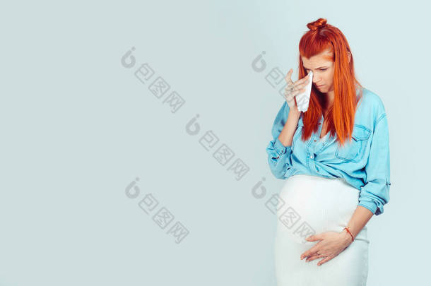 怀孕期间情绪激动。年轻的休闲妇女抚摸着温柔的婴儿在腹部和擦眼泪与纸组织看着<strong>淡</strong>蓝色。混合的种族模型, 拉丁西班牙裔爱尔兰妇女