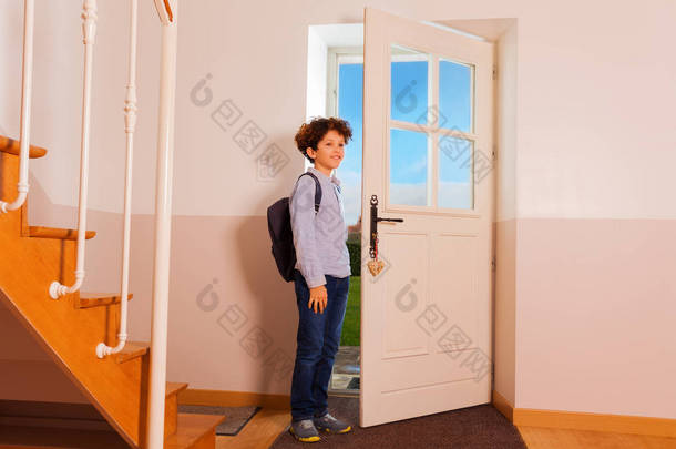 全长肖像的青春期卷曲的男孩站在走廊上, 准备出门或放学回家