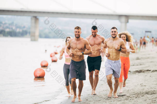<strong>一群</strong>年轻有魅力的人健身锻炼。他们玩得很开心, 在海滩上<strong>奔跑</strong>.