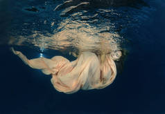 在水下长裙的年轻美丽的女人