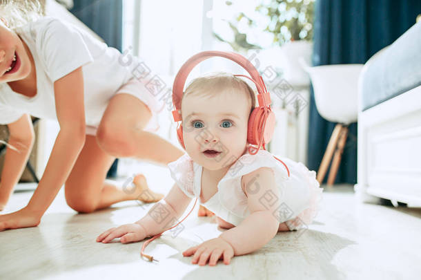 可爱的小婴儿<strong>坐在地板上</strong>, 在家玩耳机