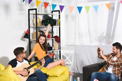 男子与智能手机摄影朋友玩吉他和唱歌在家庭聚会上