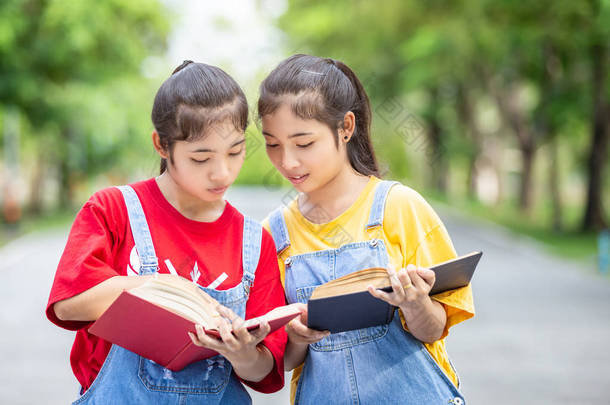 漂亮的亚洲双胞胎女孩或<strong>学生</strong>在公共公园<strong>看书</strong>。使用的<strong>教育</strong>概念