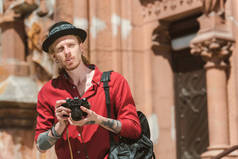 年轻男子与背包拍照在城市的相机