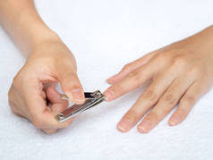 妇女切割指甲使用指甲剪在白色的背景。健康和生活方式概念.