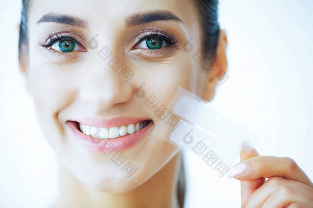 健康和美丽。美丽的年轻女孩与白色的牙齿持有在手的条纹牙齿美白。一个美丽微笑的女人。牙齿健康