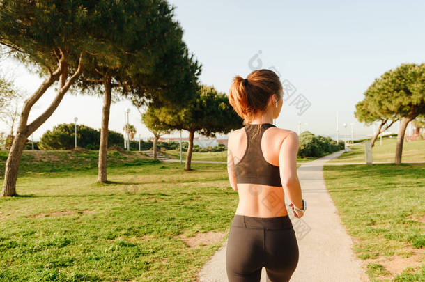 在公园户外奔跑的有吸引力的年轻体育妇女的后面看法<strong>相片</strong>.