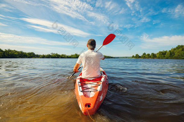 快乐的成年男子在阳光明媚的早晨在河上划独木舟, 周末享受生活用水运动。广角, 后视图.