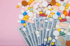 美元和药丸在粉红色的背景。医药行业美元处方药高成本医疗保健和药物的概念, 顶级视图.