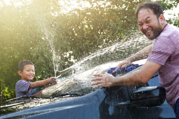 快乐的亚洲男孩帮助父母洗车的水溅着阳光在家里, 慢动作。家庭活动假期.