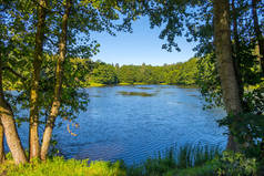 湖的蓝色水面与谷仓在森林在晴朗的天