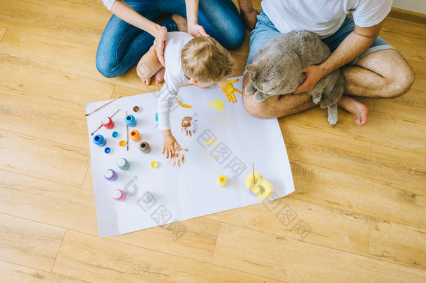 快乐的家庭和一只猫画一张海报, 另一只用颜料