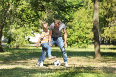 快乐的父亲和儿子在公园踢足球