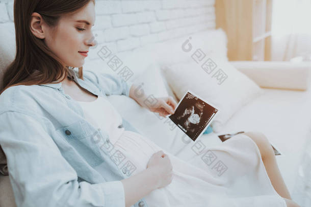 沙发上的孕妇可进行超声波扫描。快乐的母亲概念。健康怀孕的概念。年轻的母亲。期待新的生活。产妇概念。微笑的女孩。医疗照片.