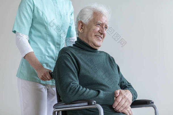 快乐的老人在轮椅和护士帮助他