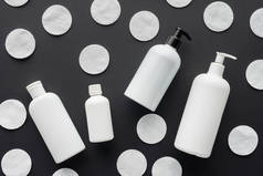 从黑色, 美容概念的分散瓶奶油和化妆品棉垫的顶部视图