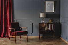 真正的照片, 一个复古客厅的角落, 在一个红色的扶手椅旁边的木制橱柜典雅, 米色灯