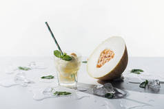美味的夏日饮料, 薄荷和瓜在玻璃, 融化的冰块和半熟瓜白色