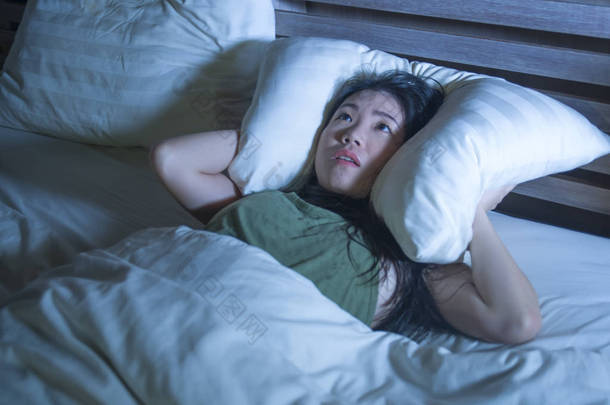 年轻美丽恐惧和压力的生活方式夜画像亚洲华人妇女躺在床上睡不着, 枕着枕头忍受噩梦失眠症和抑郁症