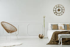 大钟挂在浅灰色的墙壁与护墙板在房间内的真实照片, 金色的椅子, 双人床和装饰