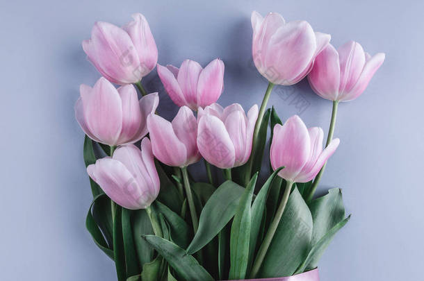 粉红色郁金香花束在浅蓝色背景。贺卡或婚礼请柬。平躺, 顶部视图, 复制空间。广泛的构成
