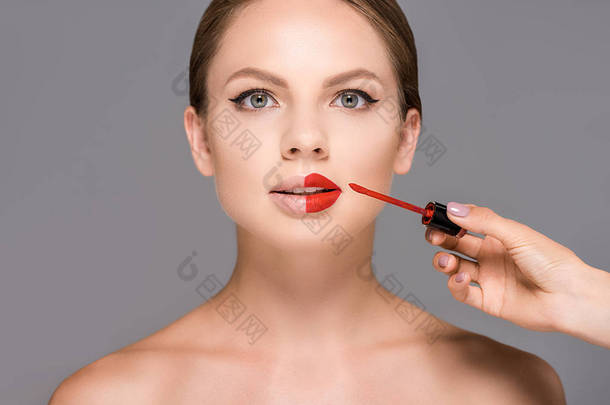 化妆师的部分观点应用红唇膏对模型嘴唇孤立的灰色