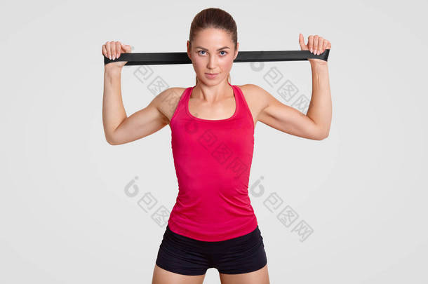 年轻苗条健身模型做锻炼与健身口香糖, 穿着<strong>休闲</strong>粉红色 t恤衫和<strong>短裤</strong>, 隔离在白色背景。有上进心的健美运动员在健身房训练。体操概念.