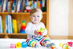 可爱的女婴在幼儿园玩教育玩具。快乐健康的孩子在家里玩五彩缤纷的玩具。婴儿发育和第一步，学习玩耍和抓取.
