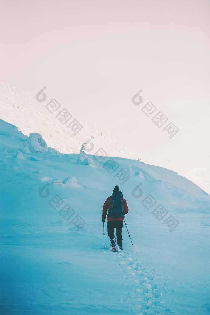 一个在雪和徒步旅行的人在山中坚守。寒假旅行。攀登一个登山者对一个美丽的天空与云。积极的生活方式。在雪中攀登高山.