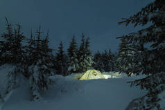冬山之夜。在雪林露营。夜风景与一个旅游帐篷在雪堆