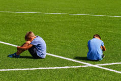 教育、欺凌、冲突、社会关系和人的概念-两个伤心失望的男孩坐在草地上的草坪上