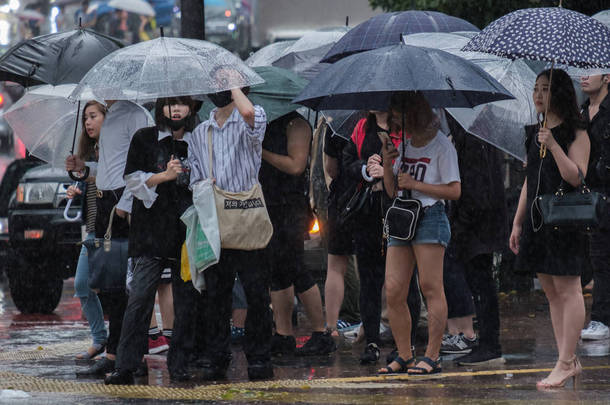 日本东京-2018年7月29日。在雨季的<strong>台风</strong>季节, 人们等着用雨伞过马路。.