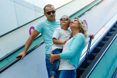 旅游理念。在机场候机楼的自动扶梯上随意佩戴的快乐家庭.