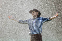 戴帽子的农夫正在享受雨。夏天雨下的年轻人被淋湿了.