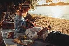 美丽的情侣享受野餐时间在日落.