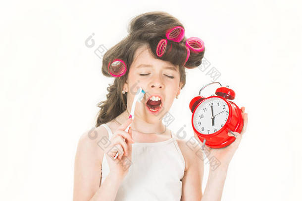 小女孩上午刷牙。穿着睡衣的小女士。小女孩拿着钟。孩子或女孩与睫毛在头发举行闹钟。少年在浴缸刷牙。可爱的小女孩, 早晨