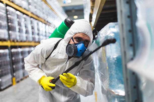 害虫防治工人手持喷雾器在生产或制造工厂喷洒农药