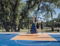 两名年轻球员在户外球场上打篮球.