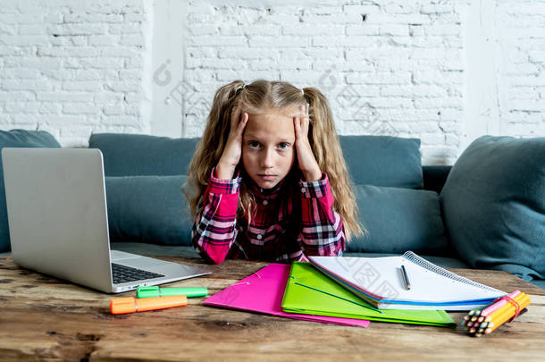 可爱的小学生感到悲伤和困惑, 而做困难的任务与她的笔记本电脑在家里。家庭作业与儿童教育理念.