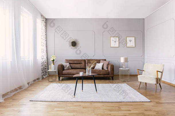 典雅起居室内配有棕色真皮沙发、时尚扶手椅、咖啡桌和灰色墙壁上的图画