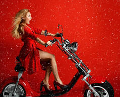 妇女骑新电动车摩托车自行车滑板车目前的新年2019红色礼服上红色背景惊讶