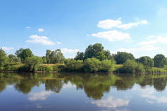 河里有干净的水。水镜反射白云。阳光明媚的日子里的美丽景色.