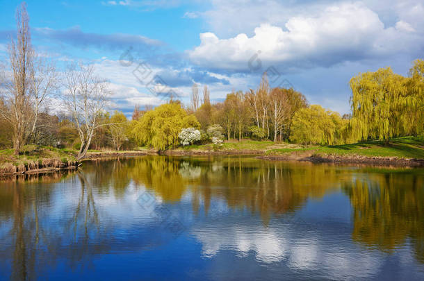 春天的风景-公园里的一条宁静的河, 树木的岸边反映在水中, 天空中<strong>乌云密布</strong>.