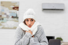 在背景的暖衣服与空调冷冻年轻妇女特写肖像