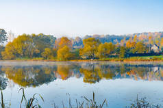湖面四周环绕着秋天的树木, 映照在湖面的镜子表面, 宁静的早晨